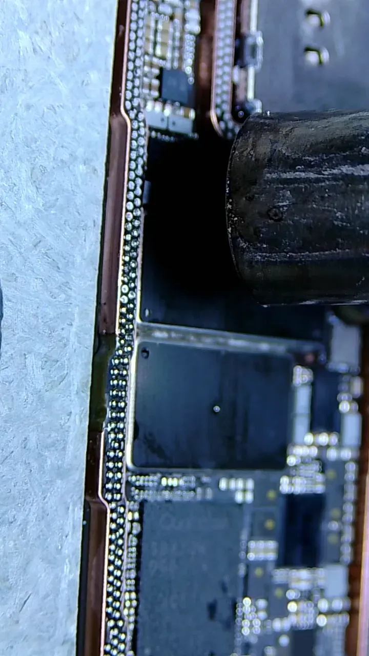 Solder balls being formed around an iPhone 15 Pro Max sandwich-board layer