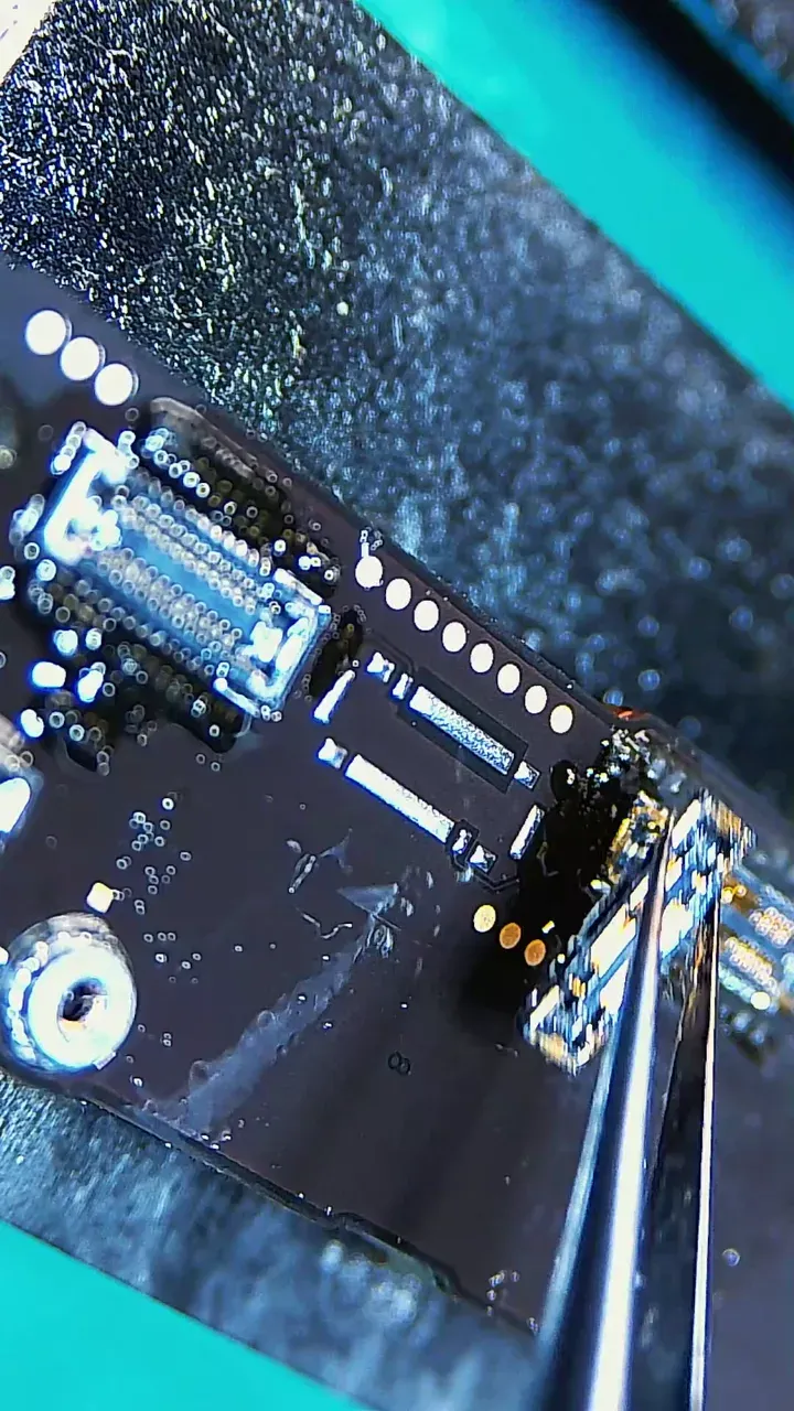 Replacement battery connector being positioned on an iPhone 16 logic board